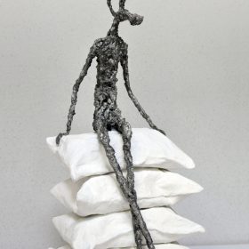 Sculpture Karine Chaudé oreillers blancs empilés et personne assis dessus