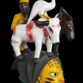 Sculpture - masque Gèlèdè - Kifouli DOSSOU - homme en jaune avec des buffles blanc et noir - cigogne blanche au dessus - visage jaune, noir, vert
