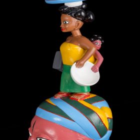 Sculpture - masque gèlèdè - Wabi DOSSOU -femme africaine avec haut jaune et jupe verte - assiette de tomates rouges sur la tête - enfant sur le dos - tient une assiette et un tabouret - visage rosé, bleu, vert, jaune - marqué sur le front et la joue