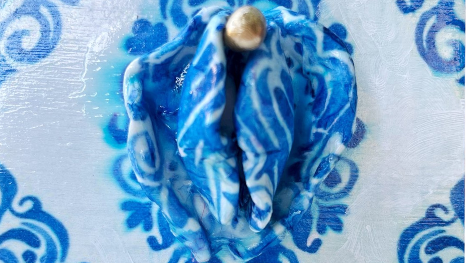 Sculpture d’une vulve avec des motifs bleus.