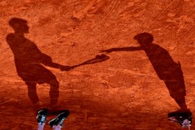 Lionel Hahn, Silhouettes, photographie des ombres de Carlos Alcaraz et d’un ramasseur de balles sur la terre battue lors de la finale de Roland-Garros 2025.